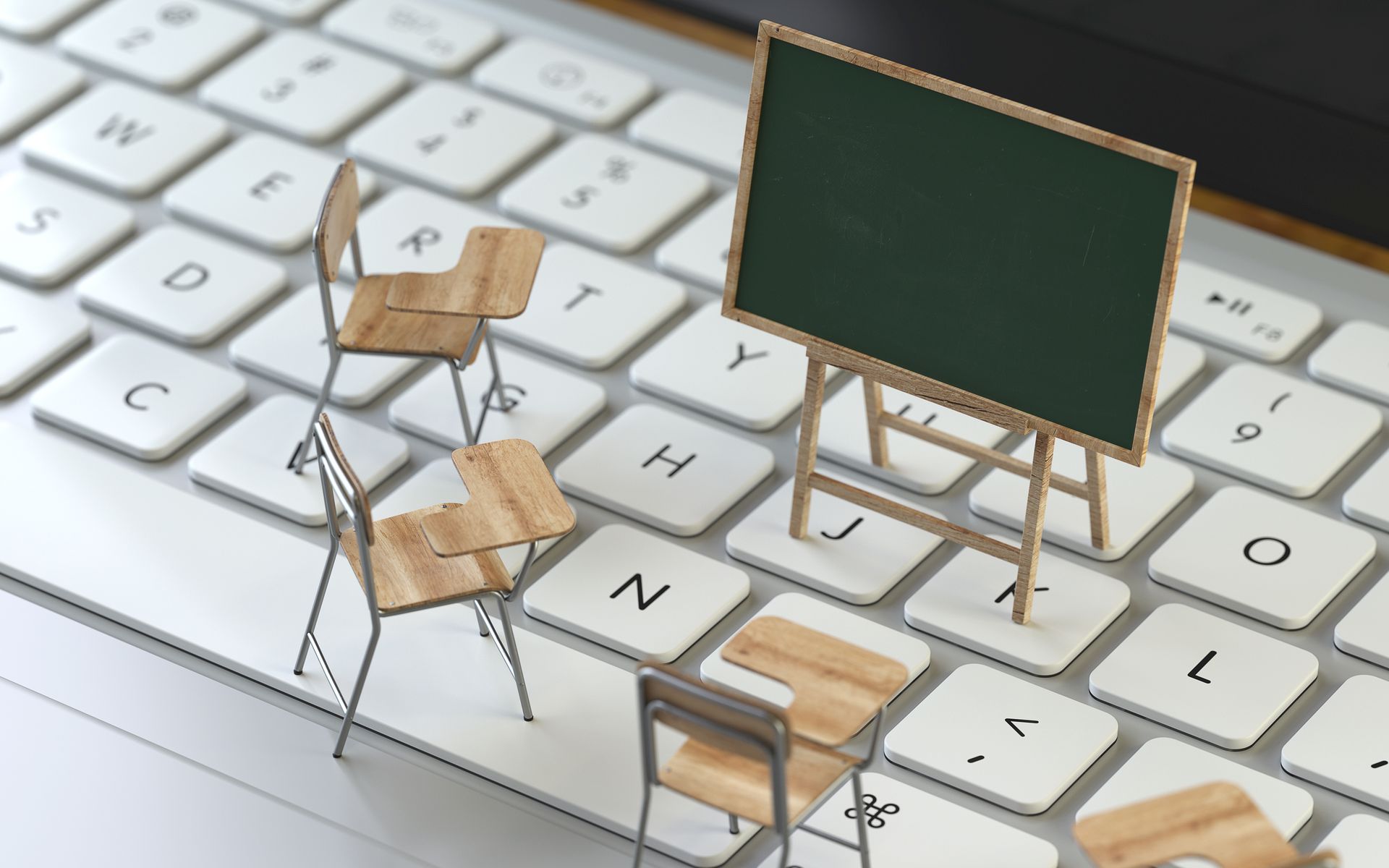 Foto von einer Tastatur, auf der Miniaturmodelle von einer Kreidetafel und Stühlen stehen.
